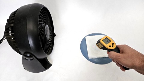 An infrared thermometer aimed at a paper towel on a plate next to a fan