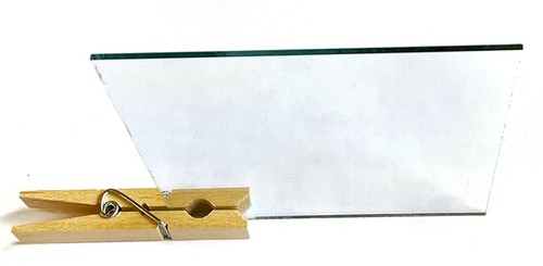  A clothespin is attached to the bottom of a mirror square to make the mirror stand up. 