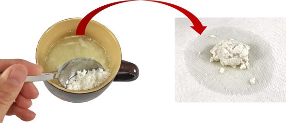 Curds are scooped from a mug and placed on a paper towel