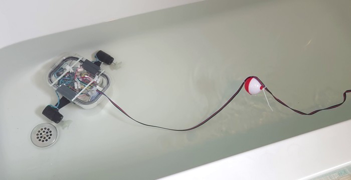 ROV in a bathtub with a fishing bobber attached to the tether a few feet behind the ROV 