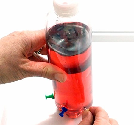 A hand gently holding the bottle while another hand pushes a pin in body of the bottle.