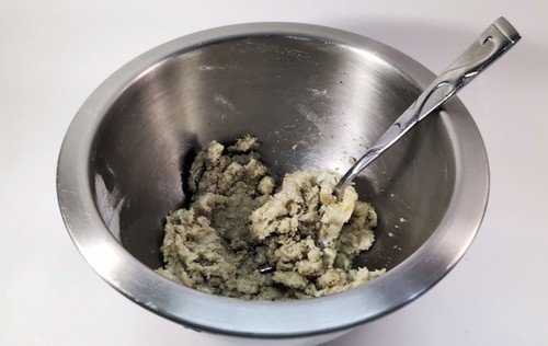 Large mixing bowl with cookie batter with chocolate chips mixed in.
