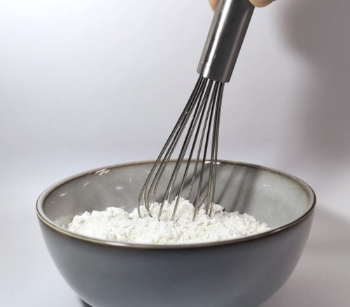 Whisking bowl of dry cookie ingredients: flour, baking soda, sugar.