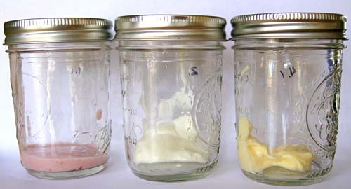 Three glass jars each contain yogurt of different colors