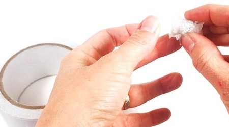 Hands placing double-sided tape around an aluminum ball.