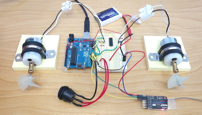 An Arduino, breadboard circuit, two underwater thrusters, lithium ion battery, power switch, and RC receiver