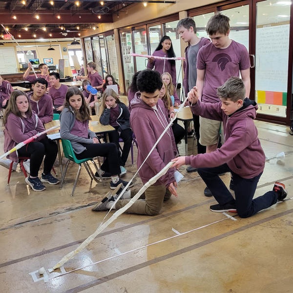 Students watching another student test a device for the Ping Pong Pickup Challenge
