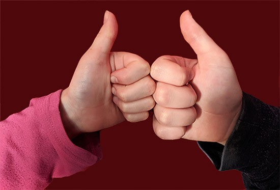 childs's hand and adult's hand with thumbs up 