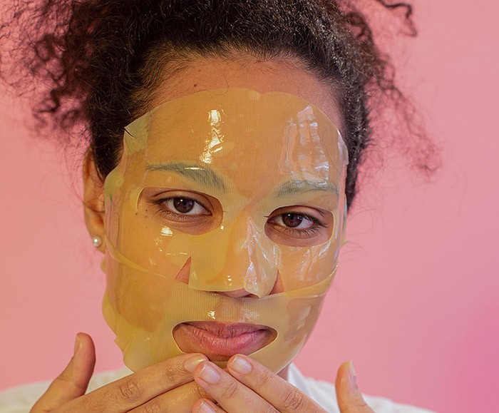 woman applying a collagen hydrogel mask with two hands