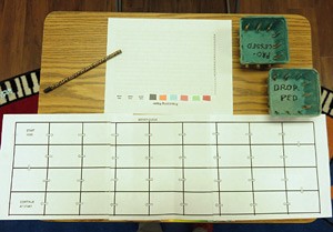 Overhead view of a pencil, paper grid, processing paper, and two boxes on a wooden desk