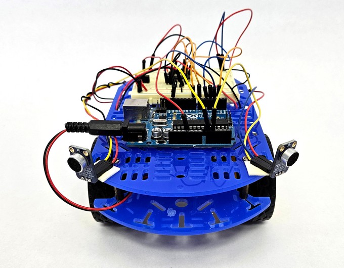 Robot chassis facing the camera, with two microphones mounted on its left and right sides toward the front, facing diagonally outward