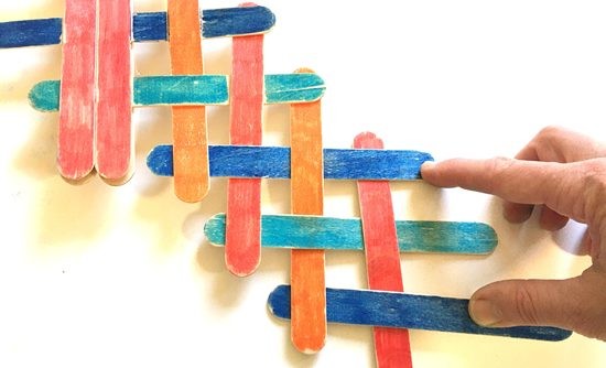 Interlaced popsicle sticks held down by a hand