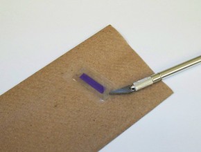 Using a pencil eraser to press down parafilm around the edges of a glass slide.