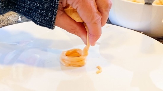 A third layer of icing being laid onto the second layer, making a little tower.   