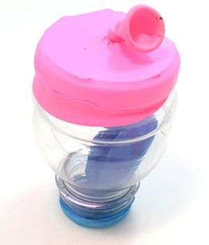 A picture of the upside down bottle with the cut balloon stretched over the large opening of the bottle. The balloon forms a membrane closing the bottle. A knot in the neck of the balloon sits in the center of the membrane.