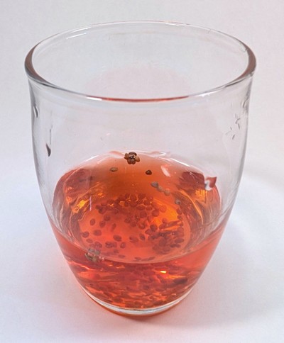 Cup with red colored sodium alginate solution mixed with seeds.