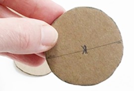 Cardboard circle with the diameter and the center marked in pencil.