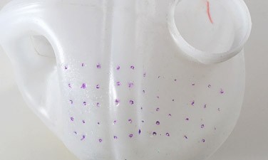 Evenly spaced dots are drawn on sides of a plastic jug