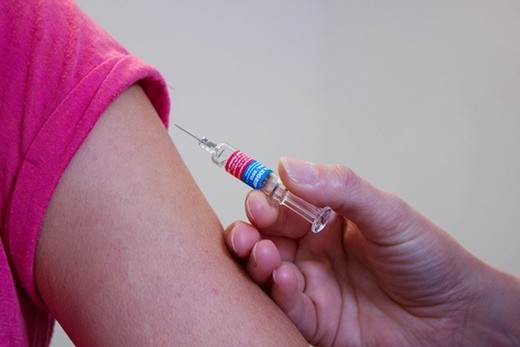 Vaccine shot being administered to someone’s bare arm.