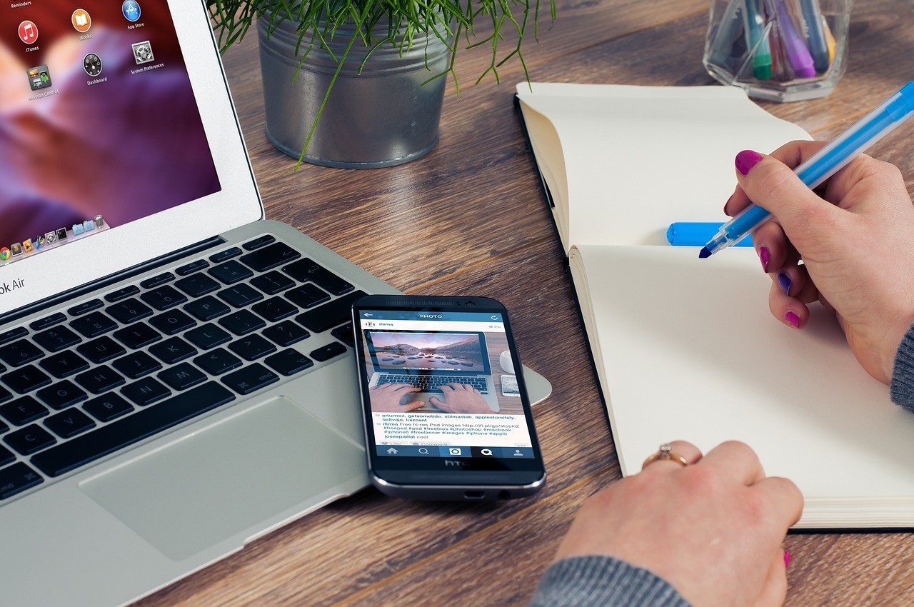  a person's hand about to write in a notebook on a table next to a phone and laptop