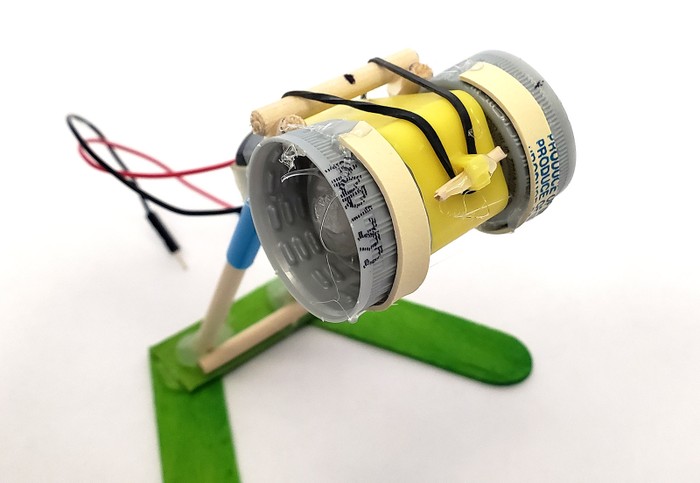 Rubber band strips glued to the edges of the bottle caps so they will rub against the wooden dowels supporting the motor.