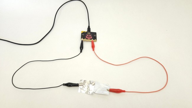 A microbit connected to a basic switch made with alligator clips and aluminum foil