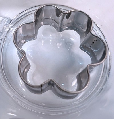 Picture of cup with cookie cutter with a little clear liquid in the bottom.