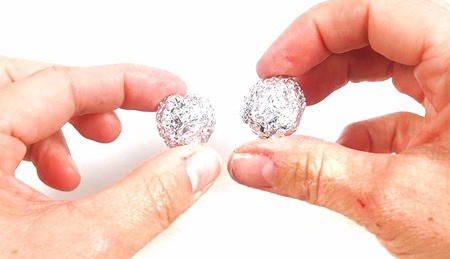 Hands holding two half-inch diameter aluminum balls.
