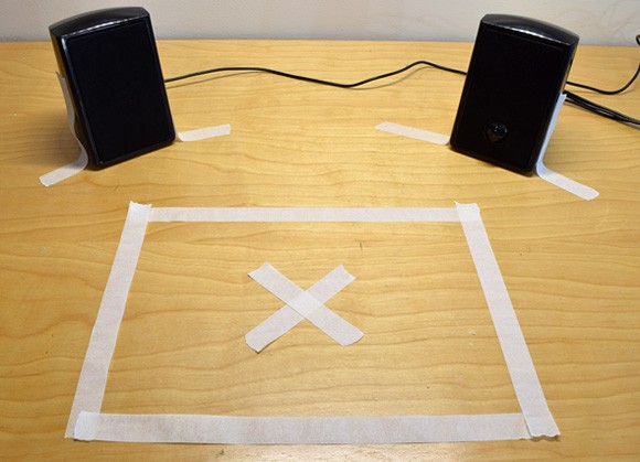 Tape marks a square area in front of two computer speakers