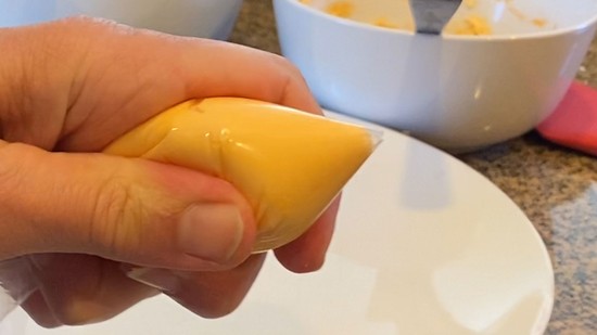 The resealable plastic bag with icing pushed towards the cut-off tip.   