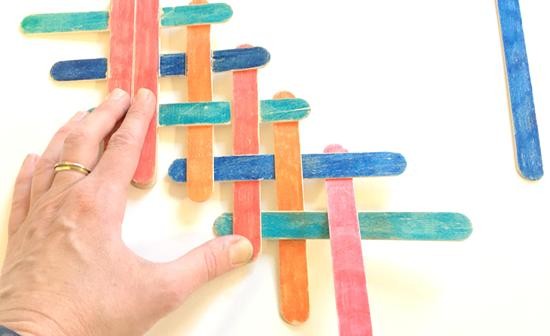 Interlaced popsicle sticks held down by a hand