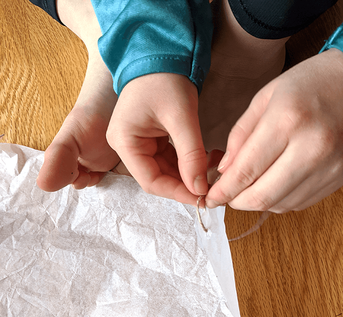 Student attaching string to a homemade parachute as part of the assembly process