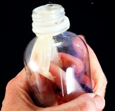Fingers rubbing the two sides of a balloon that hangs in a bottle against one another.