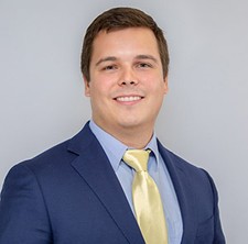 Emeric Naseman, process engineer at Fluor Corporation, dressed in a suit and smiling.