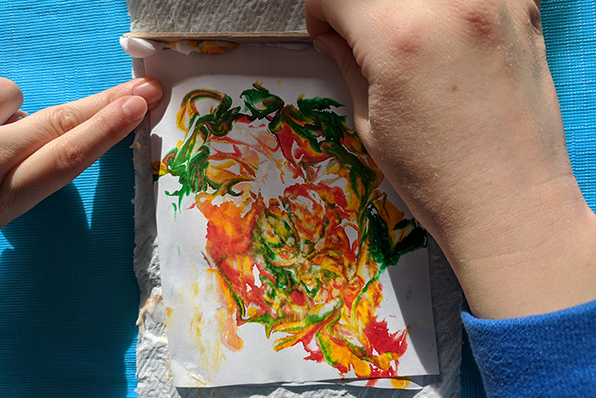 Student using shaving cream and food coloring to make paper marbling card art