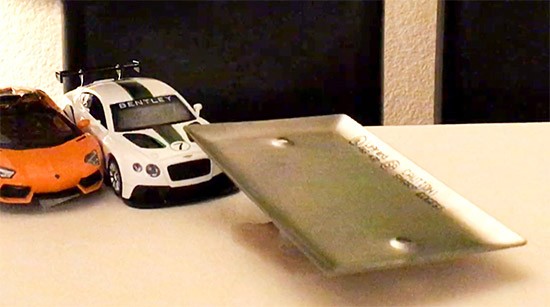 a hydraulic lift sticking out from a platform. Toy cars are visible in the background.