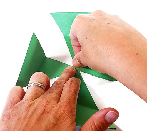 Four paper triangles spread out so that they point in four different directions and mett at their tip.