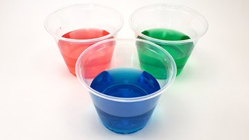 Three side-by-side plastic cups filled with red, green and blue water