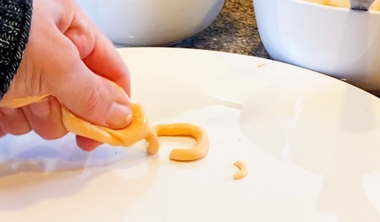  Icing being pushed out of the icing bag onto a plate. The icing outlines a square. 