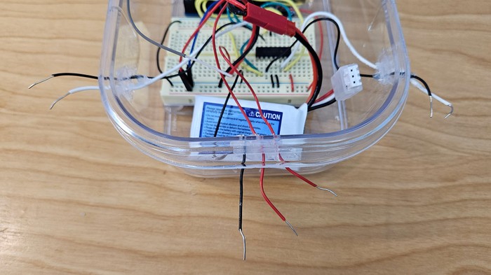 A plastic container holds the Arduino, breadboard, and RC receiver. Jumper wires pass through holes in the sides.