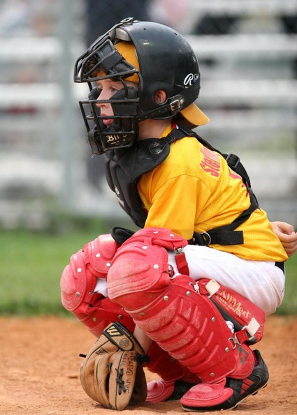 youth baseball player squatting as catcher with helmet with face mask
