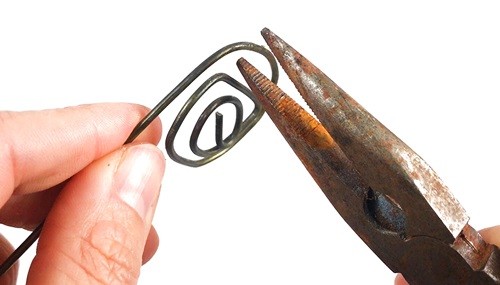 Pliers forming a spiral out of a metal wire.