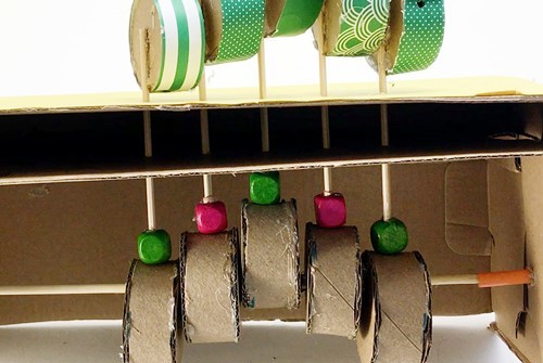 The inside of the caterpillar automaton. There are five skewers each with a bead on its end that rests on a cylinder.