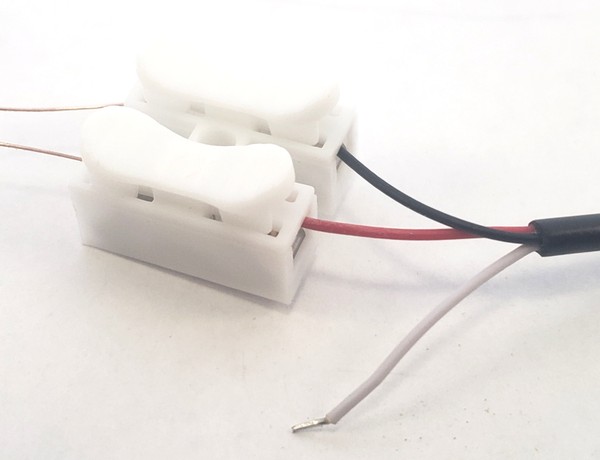 Black and red audio wires inserted into spring clips. 