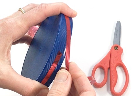 A circular lid with a ribbon wrapped around its rim.