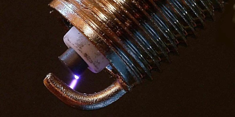 close up picture of a spark plug with a spark jumping the gap between electrodes