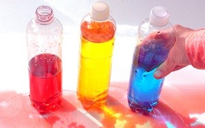 Three bottles, two of them leaking water through tiny holes.
