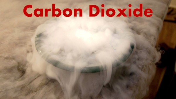 A bowl of dry ice with carbon dioxide gas spilling over the sides and all over the table.