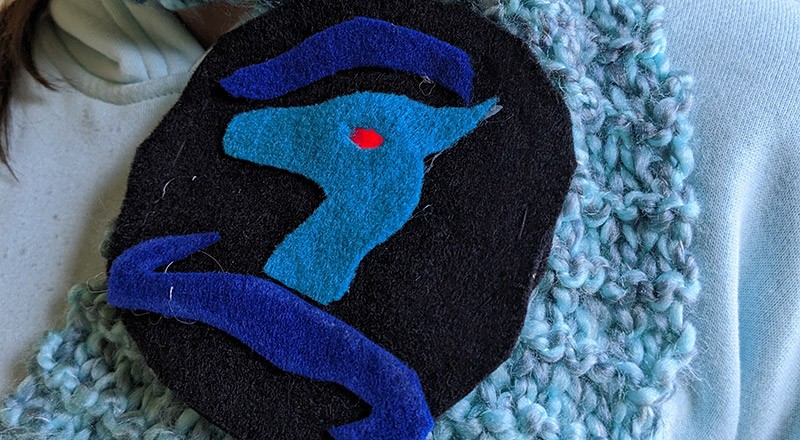 A wearable dragon badge made from felt, with an LED for the dragon's eye. 