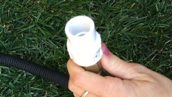 A PVC piece attached to the end of a garden hose. The free end of the adapter is a slip on piece that can be pushed onto a pipe.